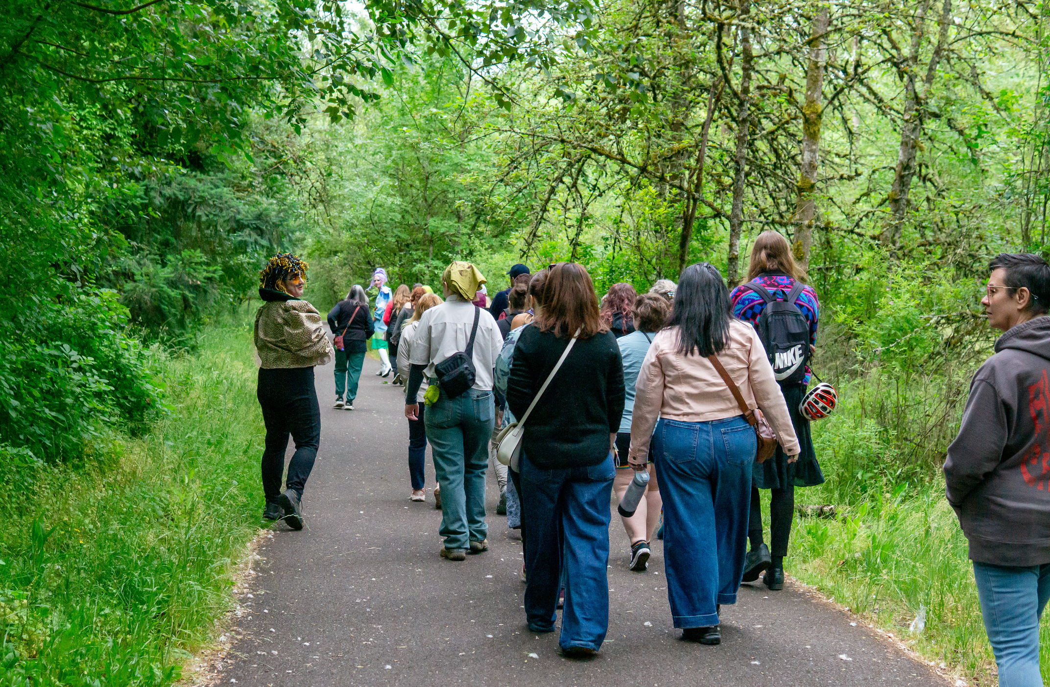 a group of people walk along a lush, paved path in portland oregon